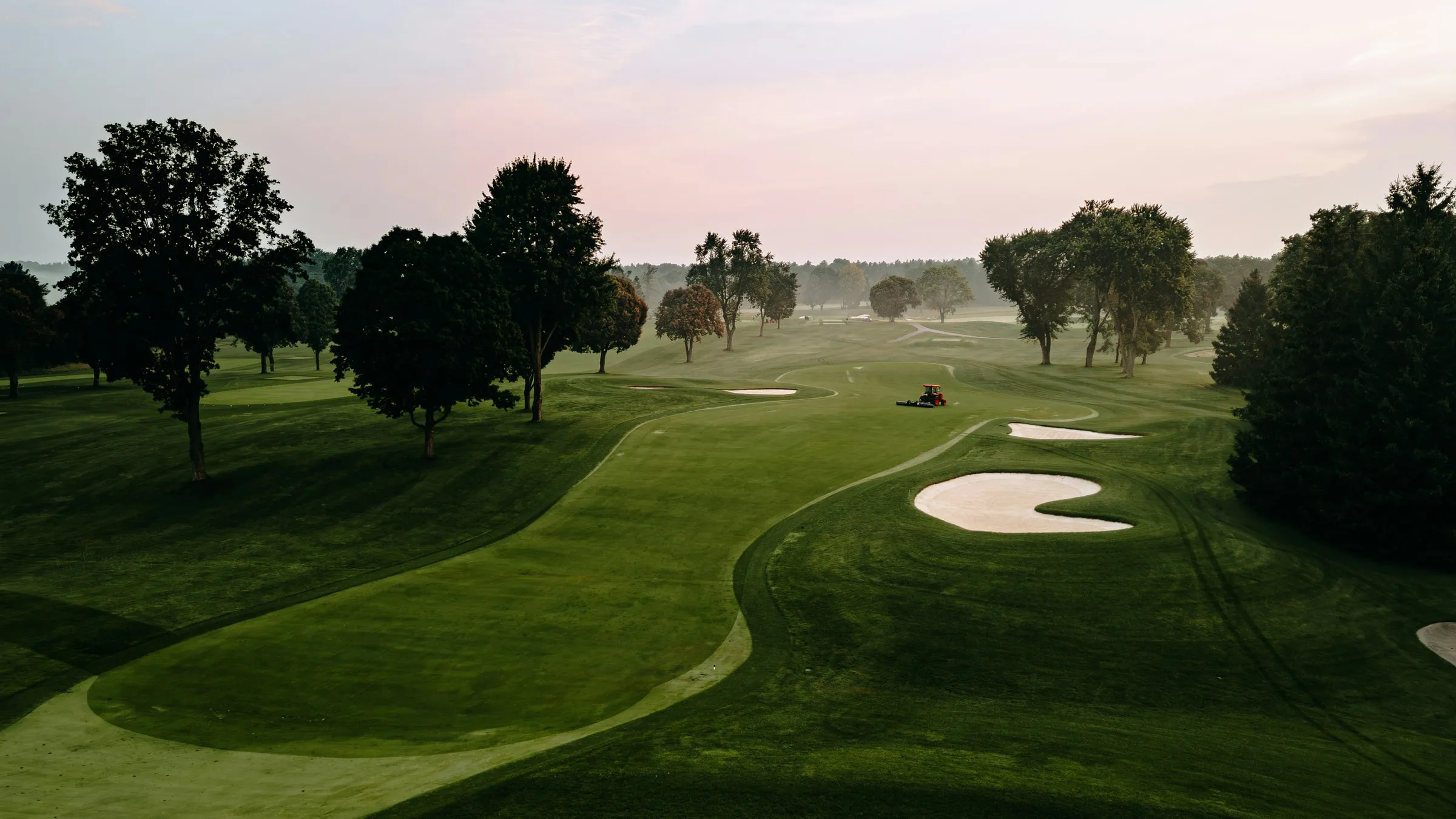 Een golfbaan met fairway en bunkers in de ochtendmist