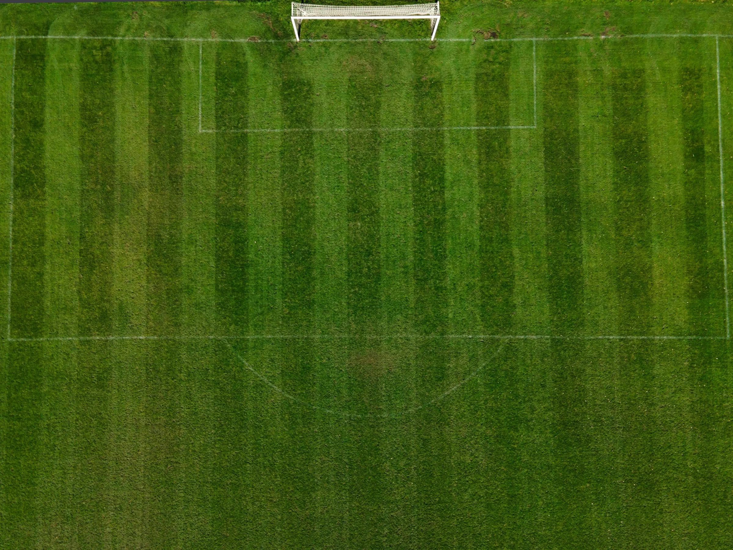 Een voetbalveld met maaistroken, van boven gezien